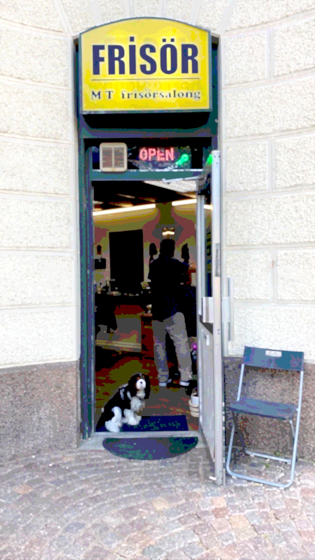 Entrén till MT Hair på Linnégatan 31 som målning, gul skylt med texten Frisör och dörren öppen